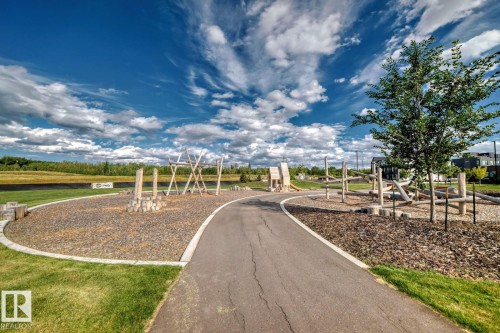 Paved pathway winding through a park area with natural wood play structures - #66 5 Rondeau Dr, St. Albert, AB - Outdoor With View