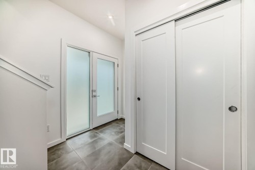 Entryway featuring frosted glass double doors, large format tile flooring, recessed lighting, and white sliding closet doors - #66 5 Rondeau Dr, St. Albert, AB - Indoor Photo Showing Other Room
