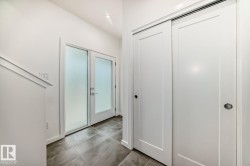 Entryway featuring frosted glass double doors, large format tile flooring, recessed lighting, and white sliding closet doors - 