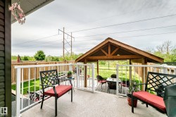 Spacious outdoor deck with white railings, a concrete surface, and a wooden gazebo - 