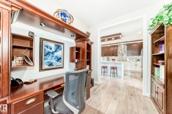 Built-in wood-finish desk and cabinetry with integrated lighting and open shelving - 