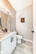Bathroom featuring a modern white vanity with a rectangular undermount sink, a chrome faucet, and a large wall-mounted mirror - 