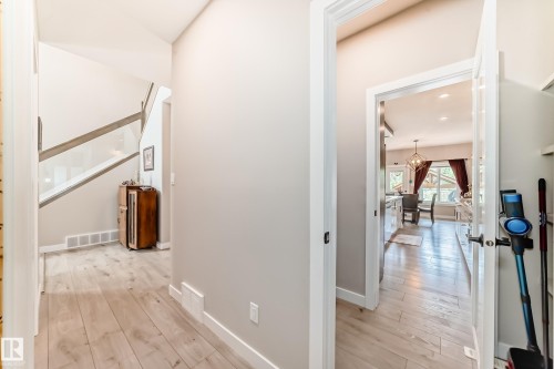 Hallway with wood-finish flooring, light neutral wall tones, and white baseboards - 3895 Robins Crescent, Edmonton, AB 