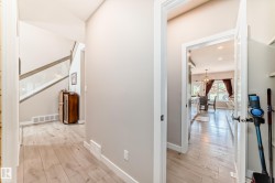 Hallway with wood-finish flooring, light neutral wall tones, and white baseboards - 