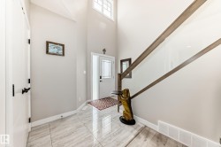 Entryway featuring vaulted ceilings, a staircase with a glass railing, and large format tile flooring - 