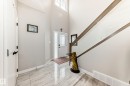 Entryway featuring vaulted ceilings, a staircase with a glass railing, and large format tile flooring - 3895 Robins Crescent, Edmonton, AB 