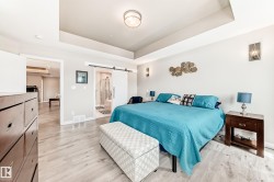 Spacious room featuring light wood-finish flooring, a tray ceiling, and modern wall sconces - 