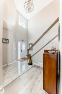 Entryway featuring a double-height ceiling, geometric chandelier, and transom window above the front door - 