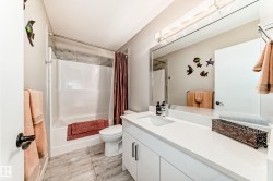 Bathroom featuring a white vanity with an integrated sink, a large mirror, and overhead strip lighting - 