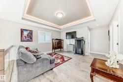 Recessed tray ceiling with perimeter lighting, light wood-finish flooring, and light neutral wall paint - 