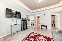 Recessed tray ceiling with integrated lighting, light wood-finish flooring, and multiple doorways - 