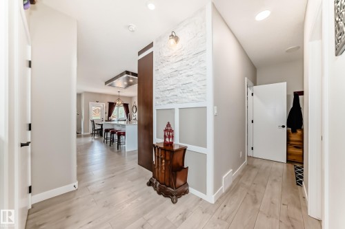 Entryway featuring light wood-finish flooring, white baseboards, and a textured accent wall with wainscoting - 3895 Robins Crescent, Edmonton, AB 