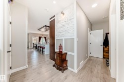 Entryway featuring light wood-finish flooring, white baseboards, and a textured accent wall with wainscoting - 