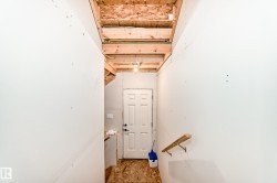 Unfinished interior space with exposed ceiling joists and subfloor, featuring a white paneled door - 
