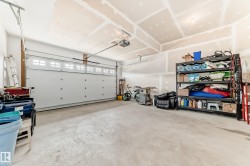 Spacious garage featuring a sectional overhead door with window inserts, exposed ceiling joists, and concrete flooring - 