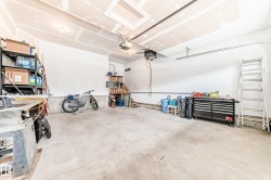 Spacious garage featuring a concrete floor, white walls, and an automatic garage door opener - 