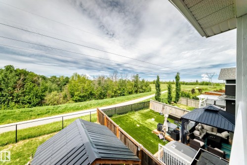 Expansive backyard featuring a lush lawn, privacy fencing, and a covered outdoor lounge area - 3895 Robins Crescent, Edmonton, AB 