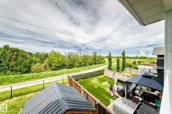 Expansive backyard featuring a lush lawn, privacy fencing, and a covered outdoor lounge area - 