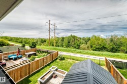 Fenced backyard featuring a raised wood deck, paved patio area, and mature landscaping - 