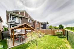 Expansive backyard featuring a manicured lawn, a covered outdoor patio with pavers, a raised wood deck, and a wood privacy fence - 