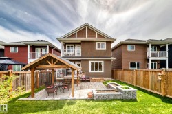 Backyard featuring a wooden gazebo with a paved patio, stone-faced raised garden beds, and a full privacy fence - 