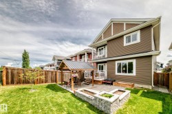 Spacious backyard featuring a manicured lawn, full privacy fencing, and a paved patio area - 