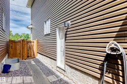 Exterior side passage featuring tan horizontal siding, a white service door, and an exterior light fixture - 