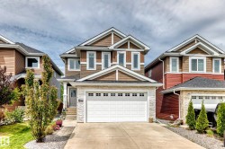 Two-story residence featuring a combination of brown siding, stacked stone accents, and white trim - 