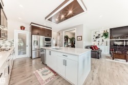 Open-concept kitchen with a central island featuring a stainless steel sink and integrated dishwasher - 