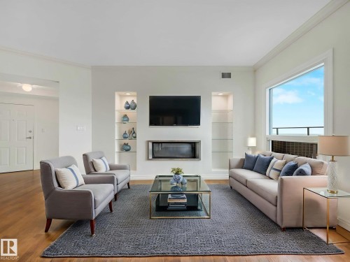 Living area featuring wood-finish flooring, a large window, and a built-in electric fireplace - 902 10108 125 Street, Edmonton, AB 