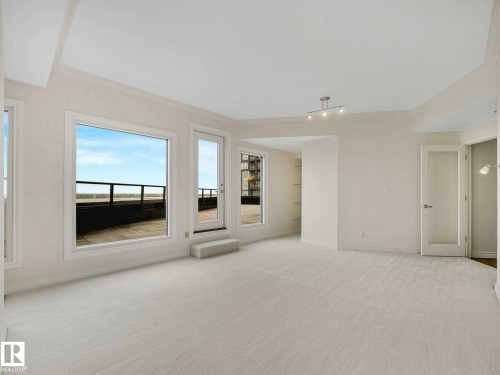 Spacious room with light-colored carpeting, multiple windows, a glass-paneled door, and a ceiling-mounted light fixture - 902 10108 125 Street, Edmonton, AB 