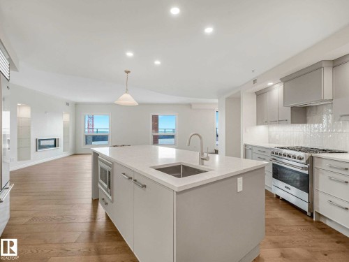 Gourmet kitchen featuring a large island with an undermount sink, built-in microwave, and pendant lighting - 902 10108 125 Street, Edmonton, AB 