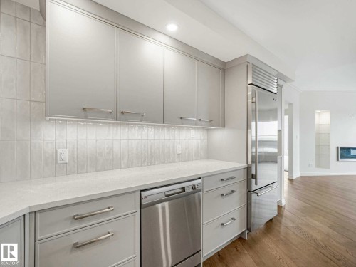 Modern kitchen featuring light cabinetry, integrated stainless steel appliances, light-toned countertops, a tile backsplash, and recessed lighting - 902 10108 125 Street, Edmonton, AB 