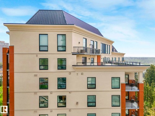 Multi-story building featuring a stucco exterior with brick accents, black-framed windows, balconies with black metal railings, and a dark metal roof - 902 10108 125 Street, Edmonton, AB 