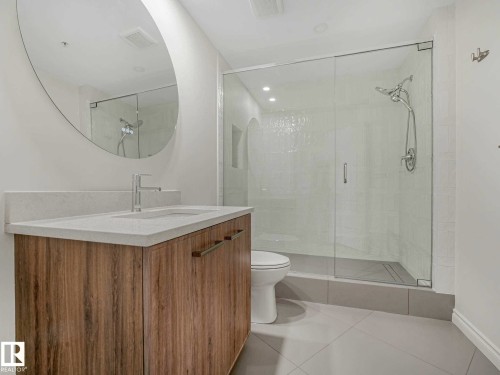 Modern vanity featuring wood-finish cabinetry, a light-toned countertop, and a sleek rectangular sink with a chrome faucet - 902 10108 125 Street, Edmonton, AB 