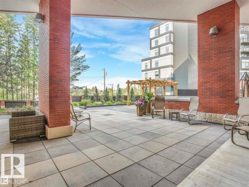 Expansive outdoor patio featuring large format pavers, brick-clad architectural columns, and integrated landscaping - 902 10108 125 Street, Edmonton, AB 