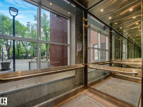 Glass-paneled elevator interior featuring brushed metal accents, recessed lighting, and a textured floor covering - 902 10108 125 Street, Edmonton, AB 