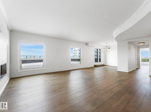 Expansive open-concept living space featuring wood-finish flooring and crown molding - 902 10108 125 Street, Edmonton, AB 