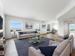 Open-concept living area featuring light wood-finish flooring, white crown molding, large picture windows, and a dedicated dining space with a chandelier - 