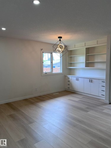 Open-concept room featuring wood-finish flooring, recessed lighting, and a modern geometric ceiling light fixture - 11911 133 Avenue, Edmonton, AB 