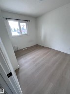 Light-filled room featuring wood-finish flooring, white walls, and a window with a black curtain rod - 
