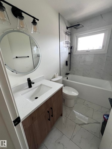 Bathroom featuring a modern vanity with wood-finish cabinetry, a white countertop, and a rectangular undermount sink - 11911 133 Avenue, Edmonton, AB 