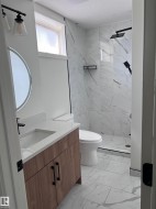 Bathroom featuring a wood-finish vanity with a white countertop and integrated sink, a rectangular shower with a clear glass enclosure, and white tile flooring - 