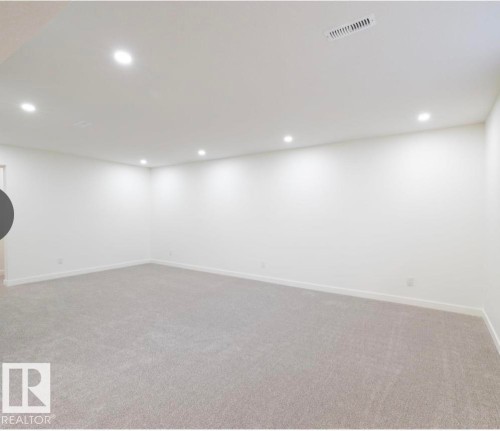Spacious room featuring neutral carpeting, white walls, recessed lighting, and a ceiling vent - 11911 133 Avenue, Edmonton, AB 