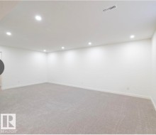 Spacious room featuring neutral carpeting, white walls, recessed lighting, and a ceiling vent - 