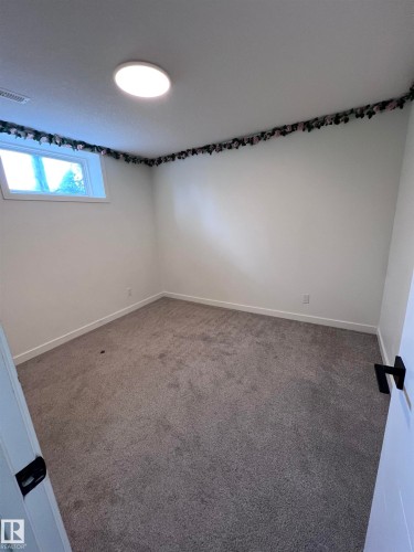 Neutral-toned room featuring a single window, white walls, and gray carpeting - 11911 133 Avenue, Edmonton, AB 