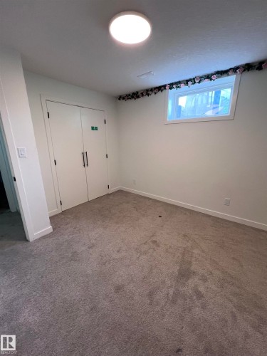 Carpeted interior space with a window and double-door closet - 11911 133 Avenue, Edmonton, AB 