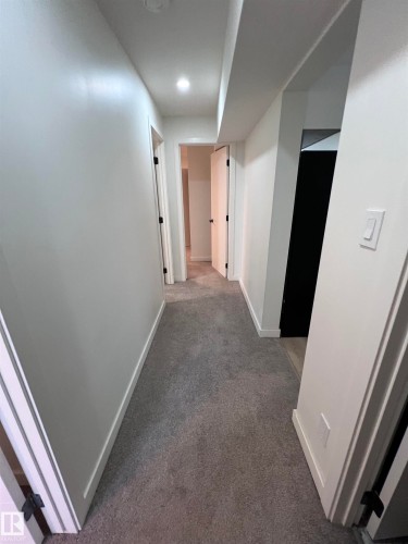 Hallway with light gray carpeting, white baseboards, and bright white walls - 11911 133 Avenue, Edmonton, AB 