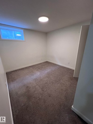 Carpeted room with white walls, a single window, and a flush-mount ceiling light - 11911 133 Avenue, Edmonton, AB 