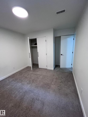 Room featuring gray carpet flooring, white walls, and a round ceiling light fixture - 11911 133 Avenue, Edmonton, AB 